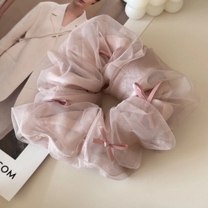 Detailed macro view of light pink mesh tulle scrunchie with delicate satin bow accents