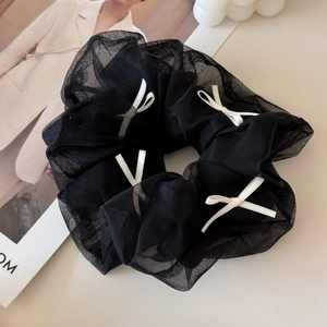 Detail shot of sheer black mesh scrunchie with white bows on an aesthetic magazine