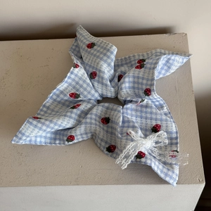 Detailed view of blue plaid hair scrunchie with strawberry patterns and lace bow trim