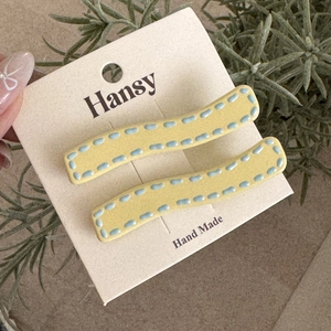 Detailed macro view of yellow wavy hair clips with blue dotted lines on display card