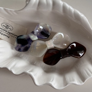 Three-piece acetate bow hair clip set in purple marble, cream pearl, and brown colors