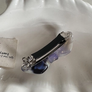 Detailed macro view of acetate hair clip with purple marble texture on ceramic plate
