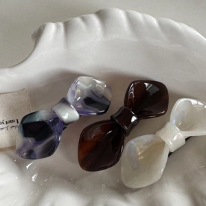 Three-piece acetate bow hair clip set in iridescent purple, dark coffee, and pearl white