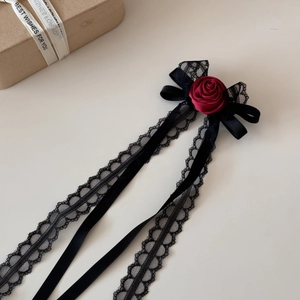 Detail of dark gothic hair clip with black lace tassels and a deep red rose flower