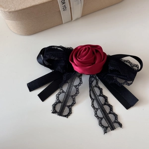 Close-up of red satin rose hair clip with black lace bow and long ribbon tassels