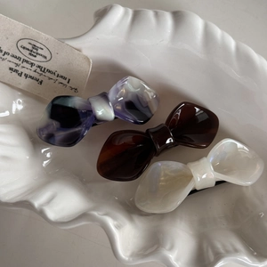 Three-piece acetate bow hair clips set in purple marble, brown, and pearly white finish
