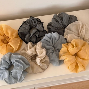 Macro detail of multicolored plaid chiffon hair scrunchies with fine pleated texture