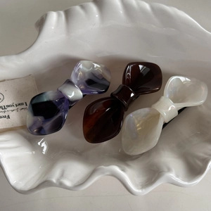 Detail view of acetate bow hair clip set in purple marble, tortoiseshell and pearl white