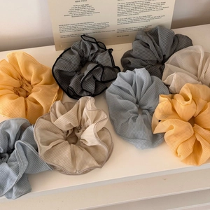 Detail showing various plaid chiffon scrunchies on a shelf with a vintage aesthetic