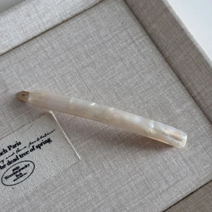 Dettaglio di un lungo fermaglio per capelli marmorizzato con testo France Handmade su vassoio