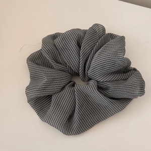 Detail of classic black and white gingham scrunchie with soft ruffled fabric texture