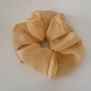 Detail view of yellow plaid chiffon scrunchie with lightweight and fluffy fabric texture