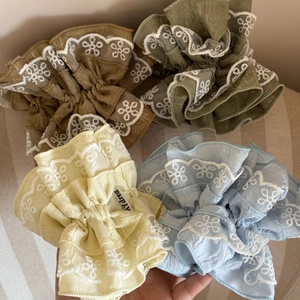 Detail of four-piece floral lace hair scrunchies in pastel colors with delicate embroidery