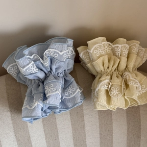 Close-up of sky blue and pale yellow floral lace scrunchies with intricate embroidery