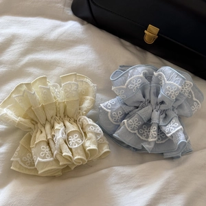 Detailed macro view of lace hair ties with floral embroidery in pastel blue and yellow