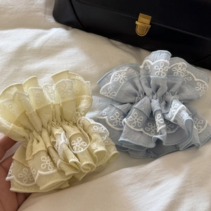 Detail of light blue and yellow lace scrunchies with elegant floral embroidery patterns