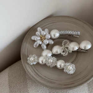 Détail de trois barrettes à fleurs en perles baroques vintage avec strass scintillants