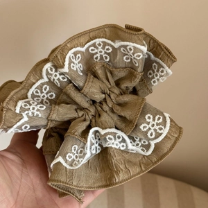 Detailed close-up of caramel lace scrunchie with embroidered daisy floral patterns