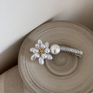 Détail de la pince à cheveux fleur en perles baroques et strass sur plateau céramique