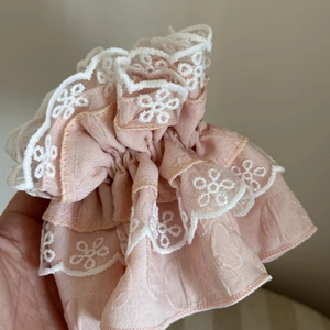 Detail view of pink layered lace scrunchie with white flower embroidery and soft ruffles