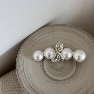 Détail d'une barrette à cheveux en perles baroques avec nœud en cristal sur céramique