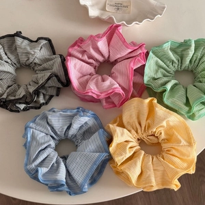 Set of five colorful striped scrunchies with ruffled edges on a clean white surface