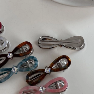Detail of acetate bow hair clips with central square rhinestone and metal snap mechanism