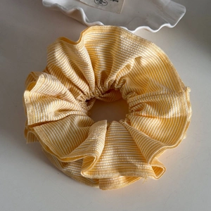 Close-up of yellow and white striped fabric scrunchie with detailed pleats and texture
