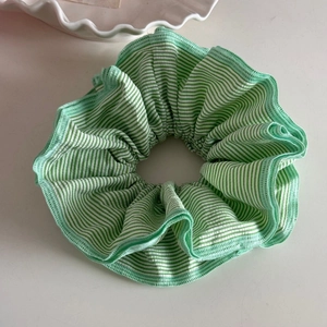 Macro shot of green and white striped fabric scrunchie with pleated ruffle details