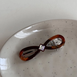 Macro shot of a tortoise shell infinity hair clip with a square diamond on a ceramic plate