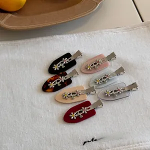 Detailed close-up of colorful flower hair clips with sparkling crystal centers on linen fabric