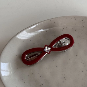 Detail of red infinity bow hair clip with square crystal and polished finish
