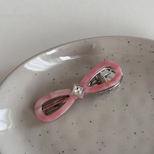 Detail of pink marble acetate bow hair clip with crystal inlay and silver metal base
