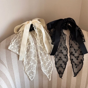 Detail of beige and black lace ribbon bow hair clips with elegant floral embroidery textures