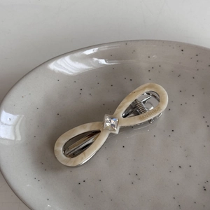 Detailed macro view of cream acetate infinity bow hair clip with rhinestone and engraving