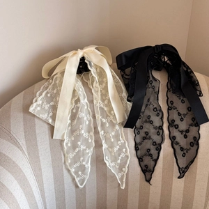 Detail of French lace bow hair clips with elegant long ribbons in black and beige