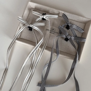Detail view of four ballet-style hair clips with striped and checkered long ribbons
