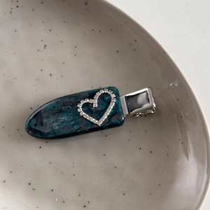 Detailaufnahme einer blauen Haarklammer aus Acetat mit einem Strassherz auf einem Keramikteller