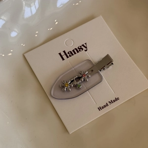 Detailed view of silver flower hair clip with colorful rhinestones on white card