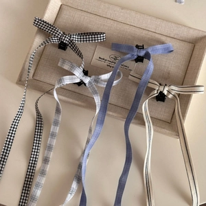 Detail view of four patterned ballet style ribbon bow hair clips on a display tray