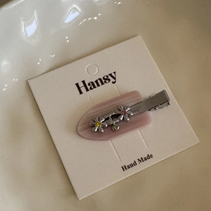 Detailed macro view of handmade floral hair clip with colorful rhinestones on a card