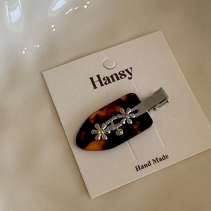 Detailed macro view of tortoiseshell hair clip with silver flowers and colorful rhinestones