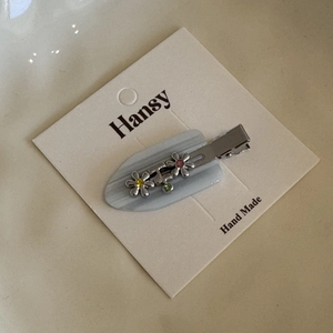 Silver metal floral hair clip with colorful rhinestones on a white gift display card