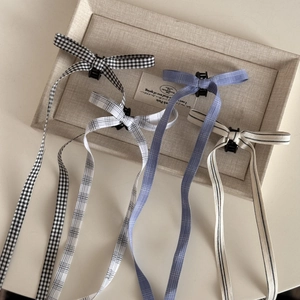 Detailed set of four ballet style plaid bow hair clips with long ribbons on a tray