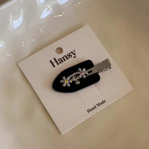 Detail of flower hair clip with colorful rhinestones on a white brand display card