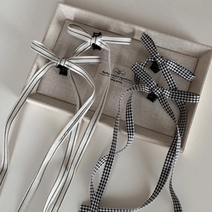 Detail of ballet style bow hair clips featuring black and white gingham and striped ribbons