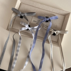 Detail view of plaid ribbon bow hair clips with long streamers in four color patterns