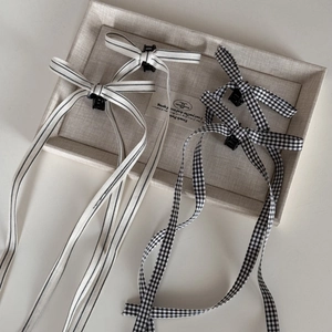 Ballet-style checkered ribbon bow hair clips with long streamers on a beige linen tray