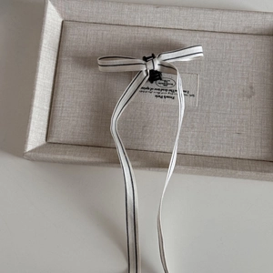 Detail of a ballet style hair claw clip featuring long ribbons on a linen display tray