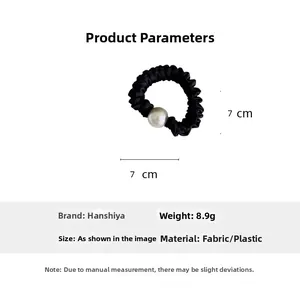 Detail view of a black ruffled scrunchie featuring a large white pearl accent